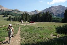 Beth departs the medicine lakes trailhead, with mt peale in the background [sat jul 7 09:58:49 mdt 2018]
